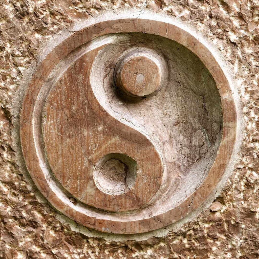 Et udskåret yin-yang-symbol i træ, som repræsenterer balance mellem modsætninger, ofte brugt i diskussioner om vrede i parforhold og følelsesmæssig harmoni.